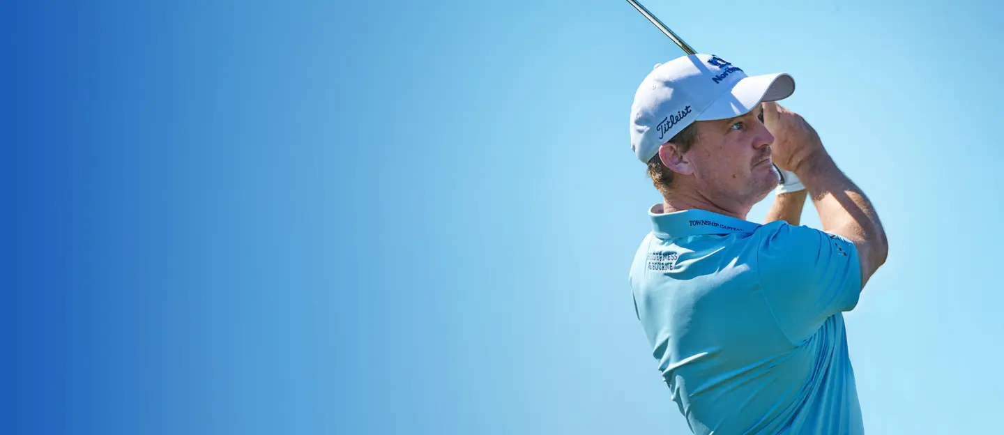 Bud Cauley Swinging golf club wearing a Northmarq hat