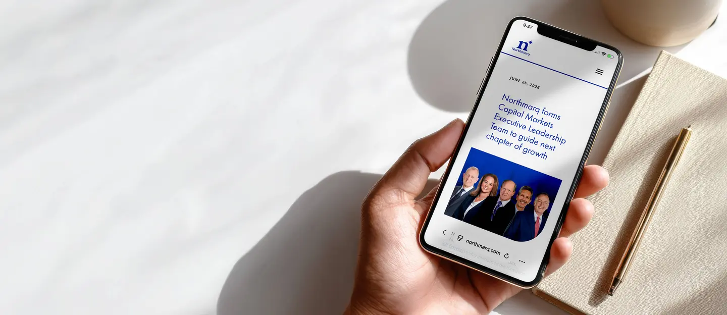 hand holding a cellphone with picture of new capital markets leaders and the headline "northmarq forms capital markets executive leadership team to guide next chapter of growth"