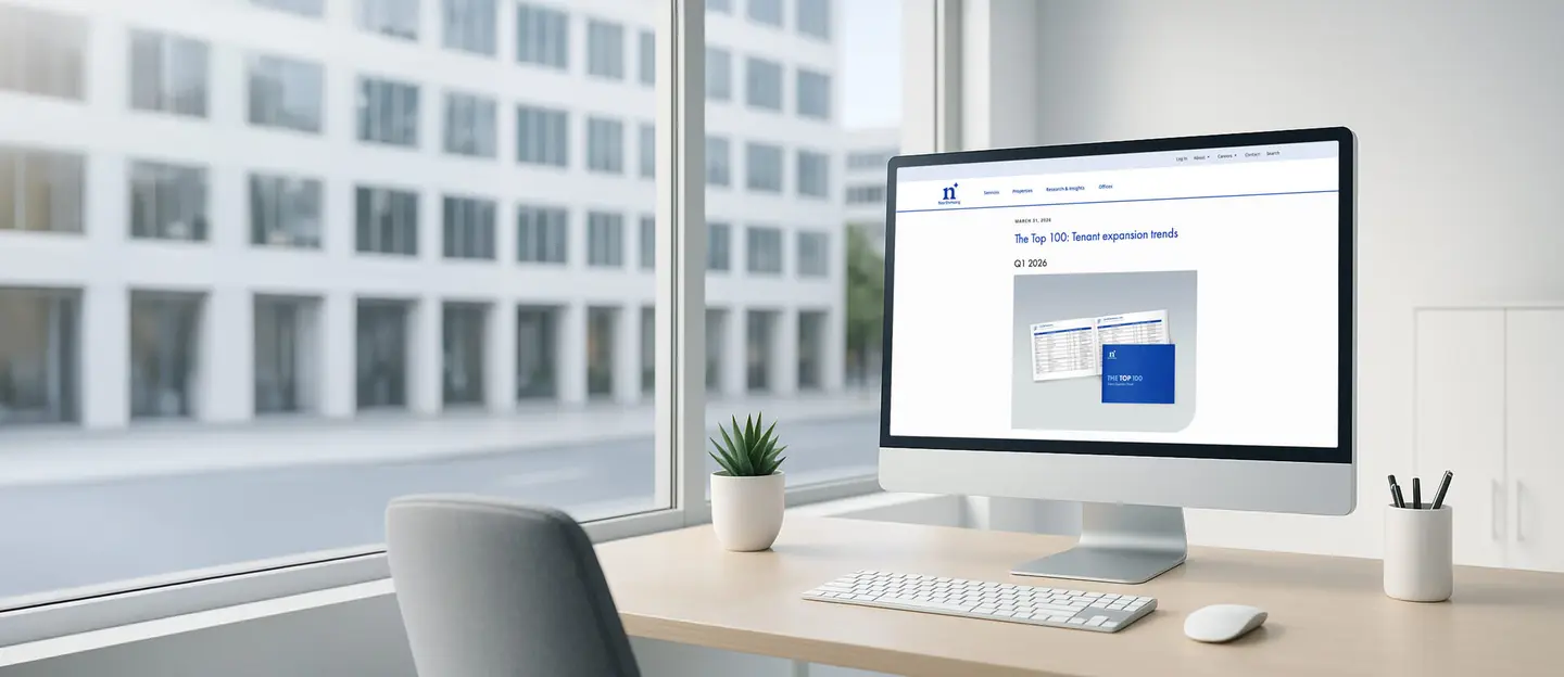 desk by a window with a computer monitor showing the top100 - tenant expansion trend report 