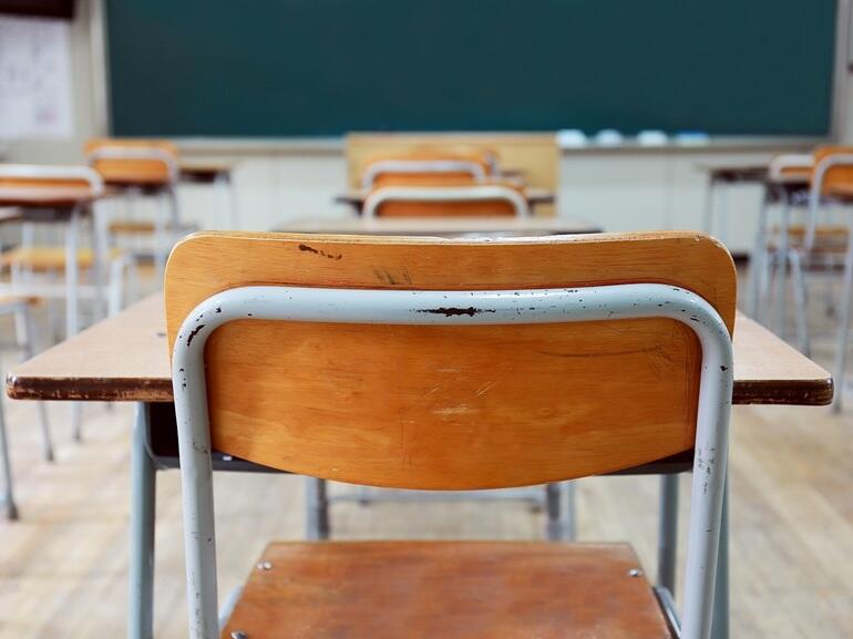 Image of an empty desk in a classroom. 