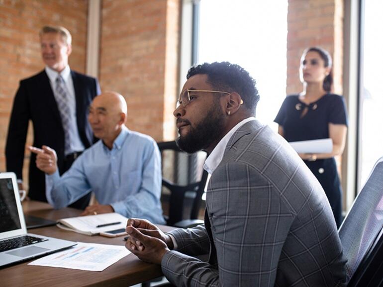 Image of individuals gathered around a table talking.