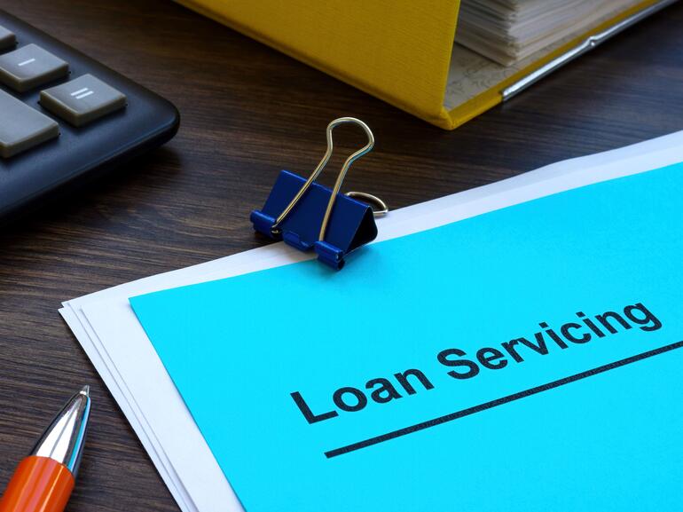 Loan servicing papers near folder and calculator
