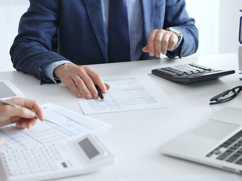 Real estate investors analyzing financing documents with a pen and calculator