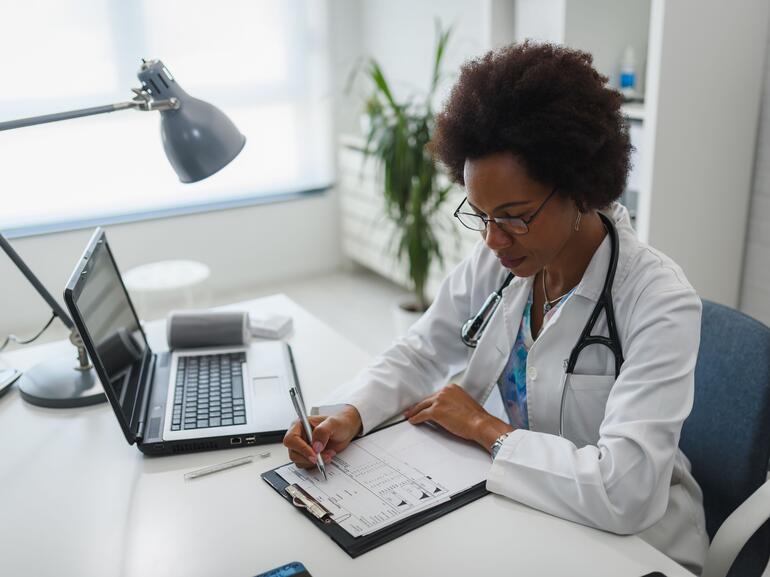 Doctor working in her office, evaluating a patient chart and lab results