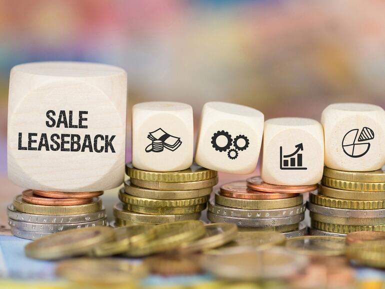 Blocks on stacks of coins that spell out sale leaseback