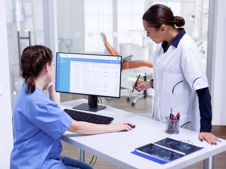 Nursing assistant reviewing patient charts with dentist in medical office