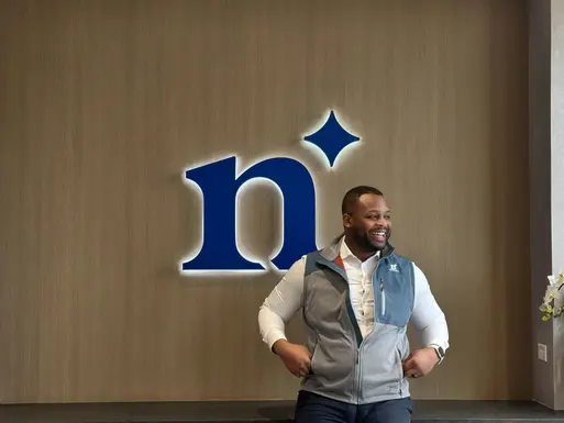 Deon Green, producer at Northmarq, standing in front of a desk with the blue Northmarq logo in the background