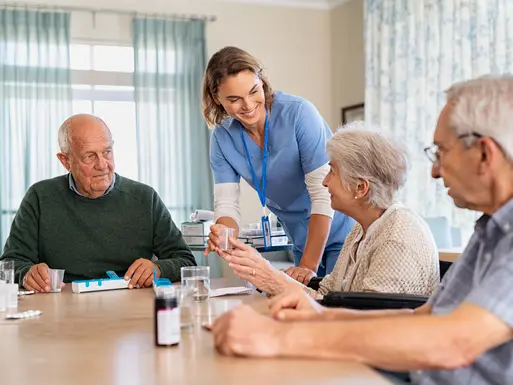 Nurse or caregiver handing medication to elderly resident of an assisted living facility