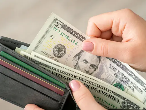 Woman pulling five dollar U.S. bill out of wallet